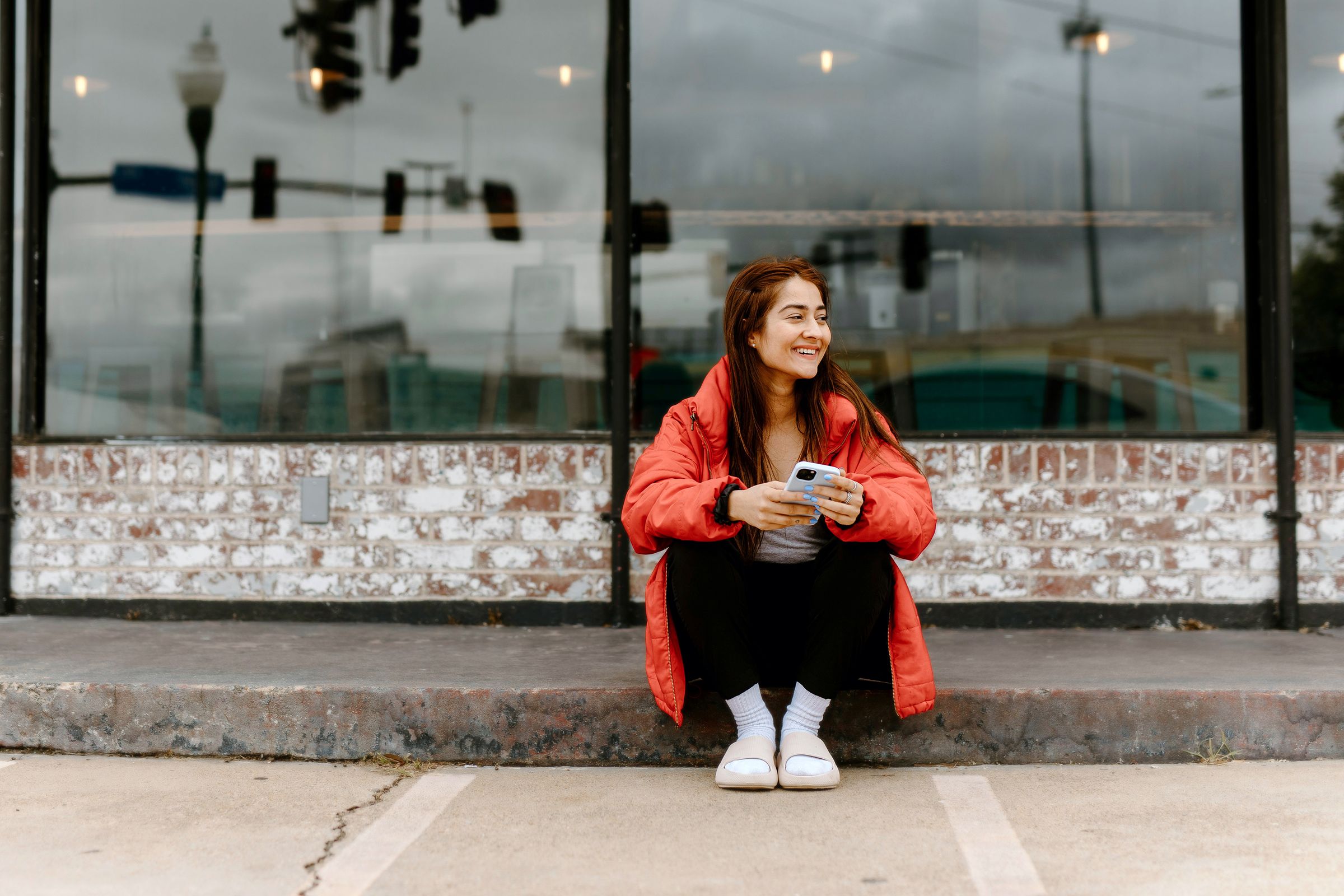 A woman smiling outdoors while holding a phone